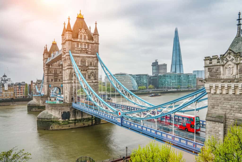 Historic Tower Bridge with red double-decker bus crossing over the River Thames in London, UK.