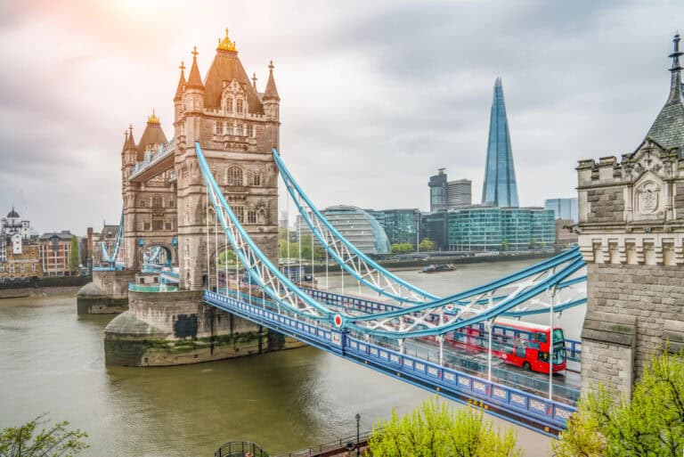 Historic Tower Bridge with red double-decker bus crossing over the River Thames in London, UK.