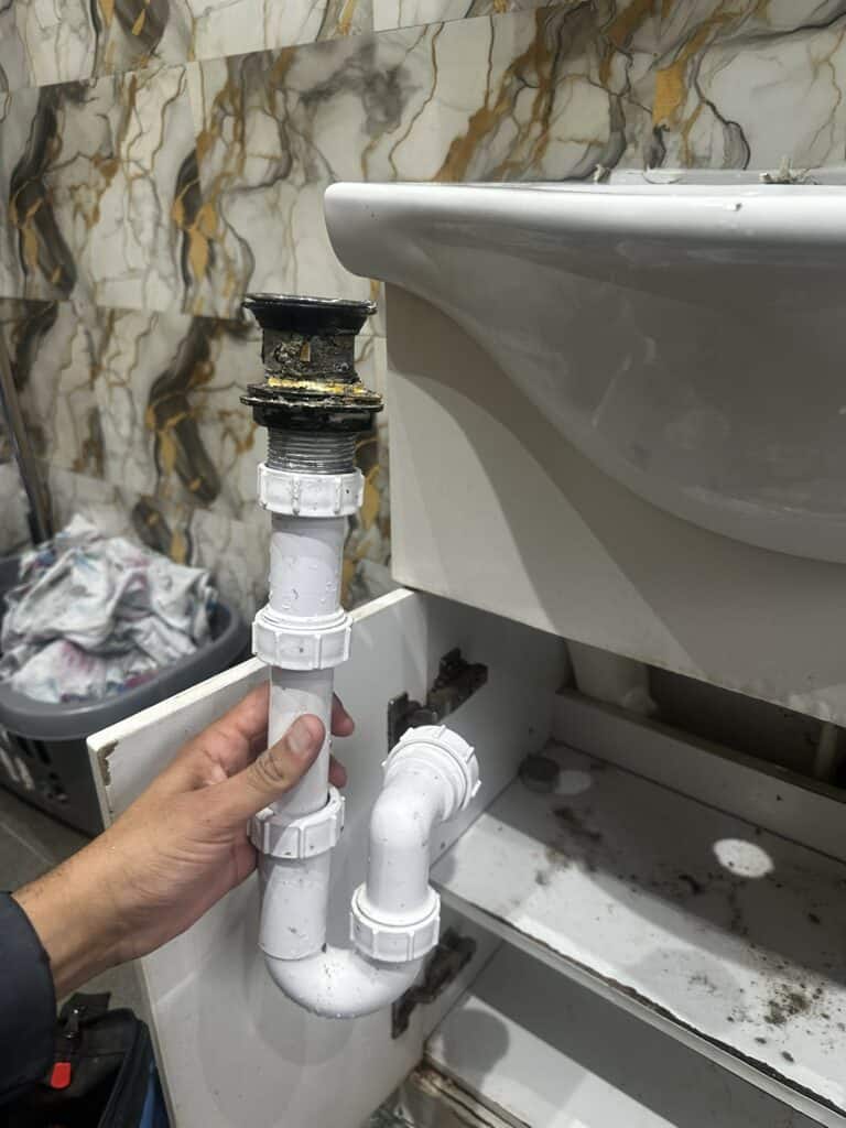 Clogged bathroom sink drain pipe with repair work in progress.